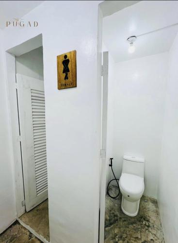 a bathroom with a toilet and a sign on the wall at Pugad Hostel, El Nido in El Nido