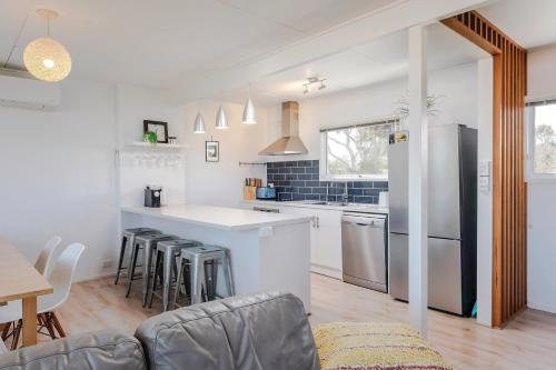 a kitchen and living room with a counter and chairs at Aldinga Beach Breakaway - C21 SouthCoast Holidays in Aldinga Beach