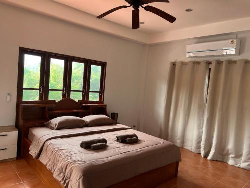 a bedroom with a large bed with a ceiling fan at Theorenda house in Ban Taling Ngam