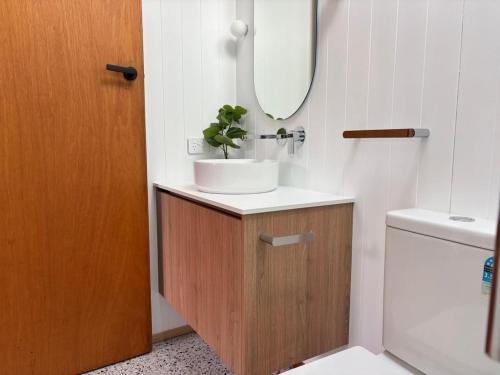 a bathroom with a sink and a mirror and a toilet at Simple Comfort: Bridport Retreat in Bridport