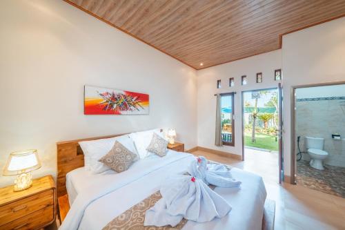 ein Schlafzimmer mit einem weißen Bett mit zwei Kleidern darauf in der Unterkunft Puspa Guest House Lembongan in Nusa Lembongan