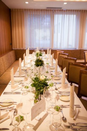 a long table in a room with glasses and flowers at Hotel Blitzburg in Brunico