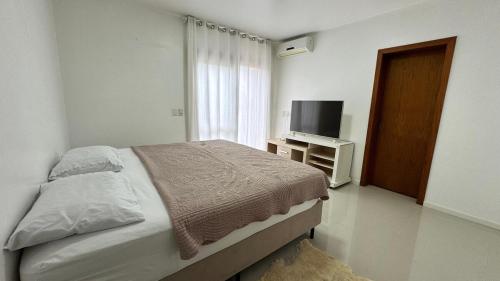 Un dormitorio con una cama y un televisor de pantalla plana. en Casa c Piscina Gigante, Lareira e Churrasqueira, en Campo Bom