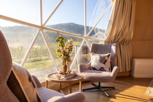 a living room with two chairs and a table and a large window at Mount Gnomon Farm in Penguin