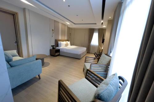 a hotel room with a bed and a couch and chairs at Belajandro Hotel Angeles City in Angeles