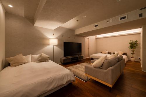a bedroom with two beds and a couch and a flat screen tv at Villa Shibuya East , 渋谷東ヴィラ in Tokyo