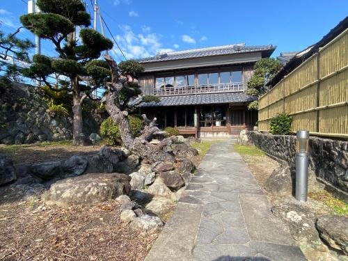 a building with a tree in front of a building at anakashico Hostel Kumano Kodo in Susami