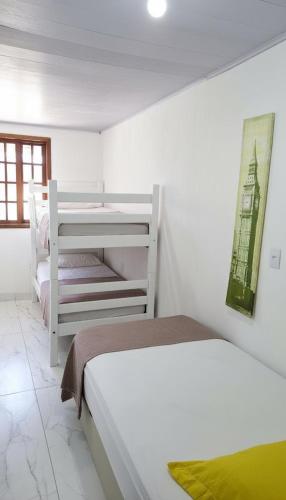 a bedroom with two beds and a painting on the wall at Casa da Angela Quarto Triplo in Rio de Janeiro