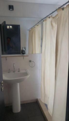 a bathroom with a sink and a white shower curtain at Villa Lastenia 2 in San Salvador de Jujuy