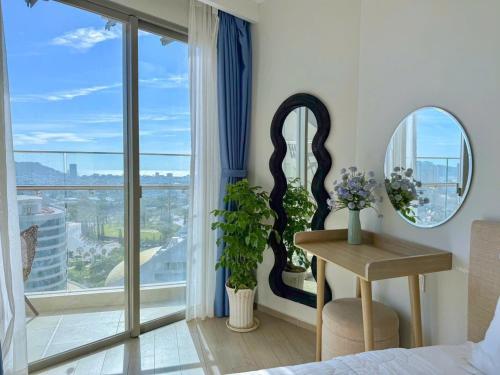a bedroom with a bed and a table and a window at căn hộ the sóng 3 phòng ngủ in Vung Tau