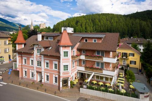 a large pink building with orange roofs on a street at Hotel Blitzburg in Brunico