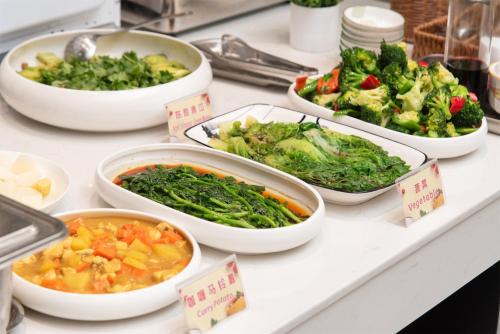 un bufé con cuencos de verduras en un mostrador en HuaHang Hotel - Free Shuttle&Free Breakfast - Guangzhou Baiyun International Airport, en Guangzhou