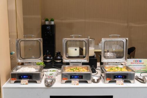 un buffet con tres platos de comida en una mesa en HuaHang Hotel - Free Shuttle&Free Breakfast - Guangzhou Baiyun International Airport, en Guangzhou