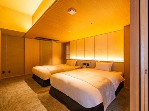 two beds in a room with yellow ceilings at AKEKURE Kyoto Shirakawa in Kyoto