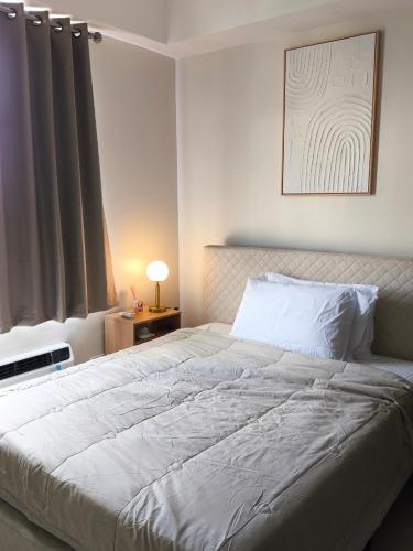 Un dormitorio con una cama blanca grande y una ventana en BH UrbanSky Condo, en Mactan