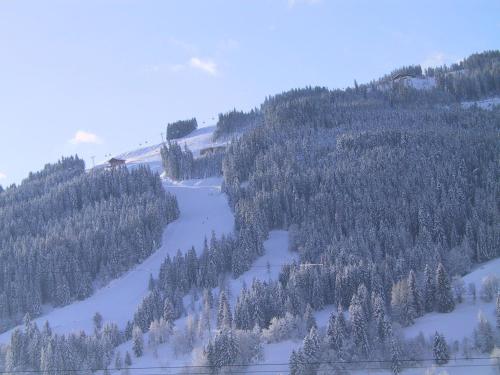 a snow covered mountain with a river and trees at Haus Katharina in Wagrain