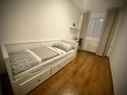 a white bed in a room with a wooden floor at 3 izbový byt KNM in Kysucké Nové Mesto