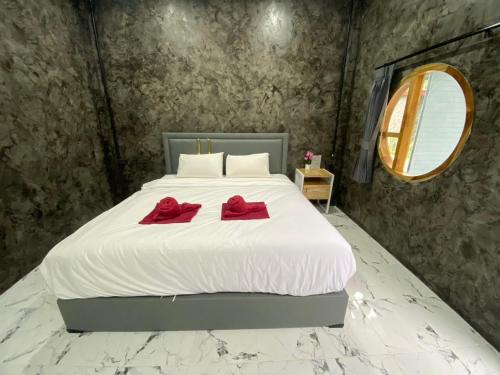 a bedroom with a white bed with two red pillows on it at Khaosok Foresta Resort in Phanom