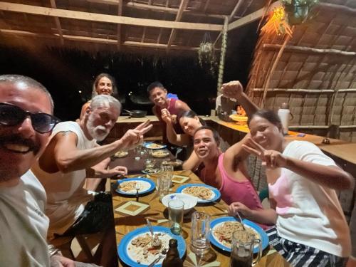 a group of people sitting around a table eating food at DANG dang Balbago Beach in El Nido