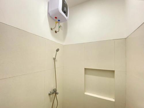 a white bathroom with a shower with a fan on the ceiling at Modern Stay near Roxy Mall Jember RedPartner in Panti