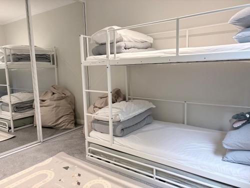 a room with white bunk beds with towels at Coastal Comfort In The Heart Of Coogee in Sydney