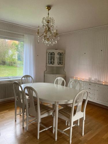 a dining room table with chairs and a chandelier at Idyllic vacation home with lakeview in Grönskåra
