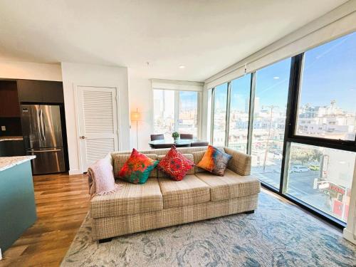 a living room with a couch and large windows at Boutique KTown Stays With Breathtaking Rooftop Views in Los Angeles