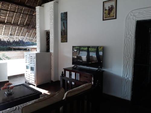 a living room with a tv and a table and chairs at Artistic Dreamsace 4Br Villa Near Diani Beach in Kwale