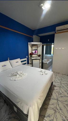a bedroom with a large bed with a blue wall at Hotel MarVinhal in Santa Maria
