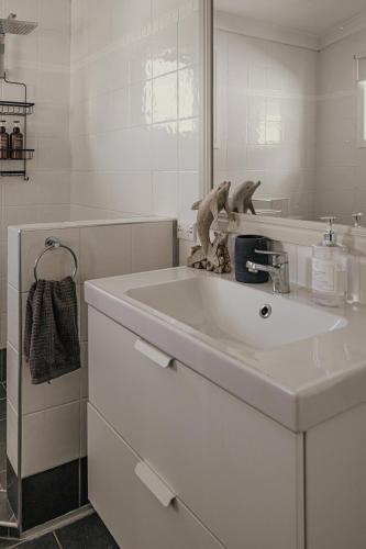 a white bathroom with a sink and a mirror at The Little River Cottage - Riverfront Retreat in Murwillumbah