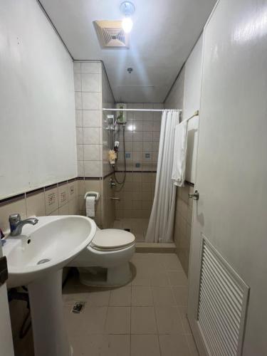 ein Badezimmer mit Waschbecken, Toilette und Dusche in der Unterkunft Robinson's Place Residences, in Manila