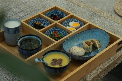 a wooden tray with bowls of food on it at Dongsheng Design Hotel in Dali in Dali