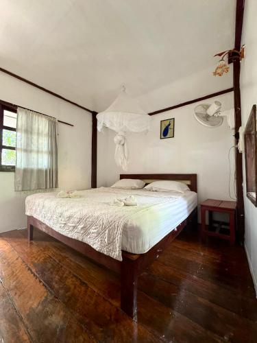 a bedroom with a large bed with a wooden floor at Tavendang Guesthouse in Don Det