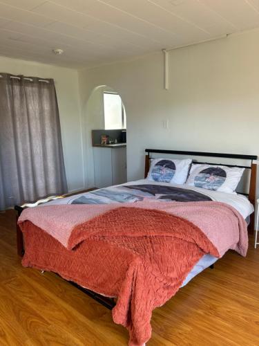 a bedroom with a bed with a red blanket on it at Granny House for rent in Auckland