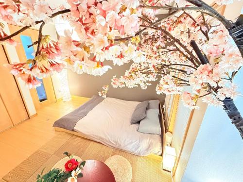 a room with a bed and a tree with flowers at AYA Funabashi#104 Enjoy the cherry blossoms in full bloom, Tatami experience, Funabashi station near by, Many restaurants & shops, Kid, Long term, Direct airport access, Messe, Disney, Cozy in Funabashi