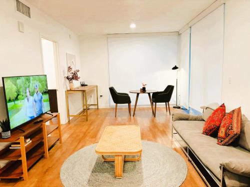 a living room with a couch and a tv and a table at Boutique KTown Stays With Breathtaking Rooftop Views in Los Angeles