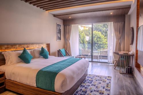a bedroom with a large bed and a large window at Soaltee Westend Lakeside Pokhara in Pokhara