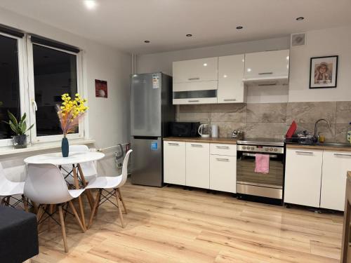 una cocina con armarios blancos y una mesa con flores amarillas en SAS Militaria dla 2 par 2 pokoje 4 osoby, en Borne Sulinowo