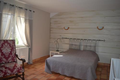 une chambre avec un lit et une chaise dans l'établissement La Bastide Des Oliviers, à Châteaurenard
