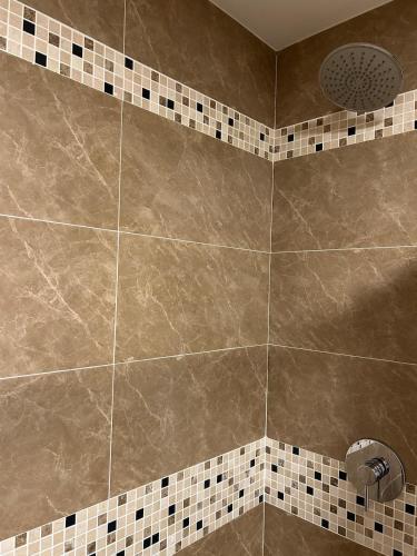 bagno con doccia e piastrelle marroni di Luxe Royal 1BR at the Vineyards w Pool & WiFi a Kingston