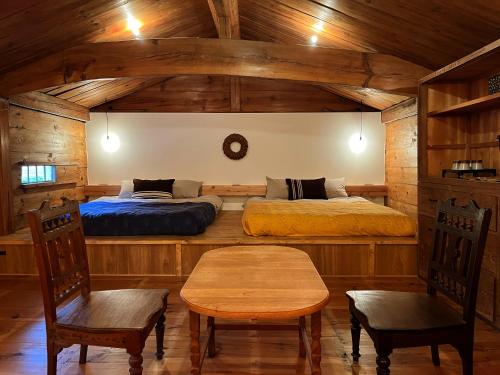 a bedroom with two beds and a table and chairs at The Bath and Bed Sakuho in Saku
