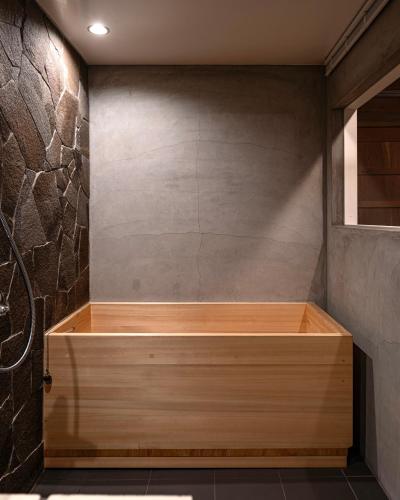 a bath tub in a bathroom with a stone wall at The Bath and Bed Sakuho in Saku