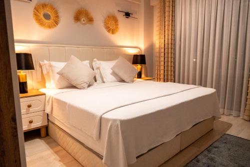 een slaapkamer met een groot wit bed met witte kussens bij BL Karakum Suites in Sinop
