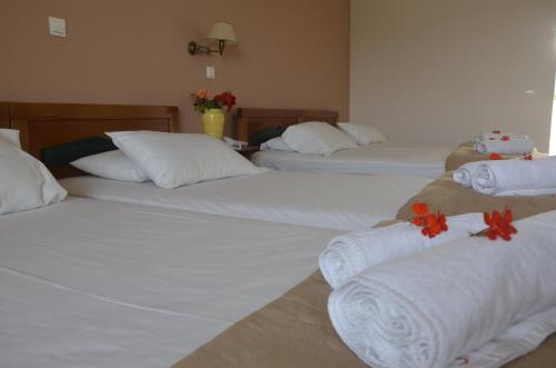 three beds in a hotel room with flowers on them at Jenny Hotel in Laganas