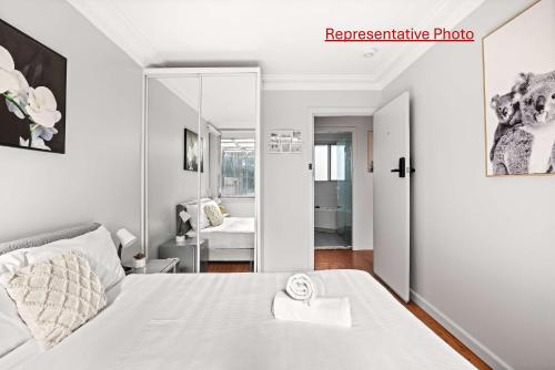 Un dormitorio con una cama blanca y un espejo. en Light & Simple Double Room - Peakhurst Area - Shared Bathroom, en Peakhurst