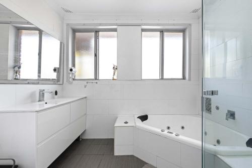 a white bathroom with a tub and a sink at Light & Simple Single Room - Peakhurst Area - Shared Bathroom in Peakhurst