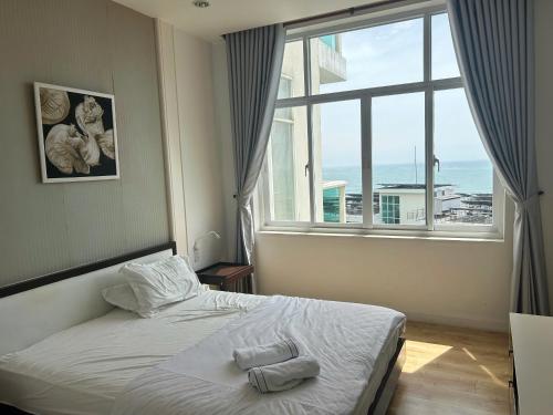 a bedroom with a bed and a large window at Ocean Vista Resort Sealink Phan Thiet in Ấp Phú Tịnh (2)