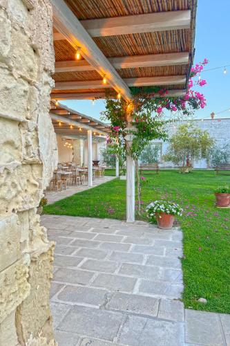 an outdoor patio with a stone wall and flowers at Masseria Rauccio in Torre dell'Orso