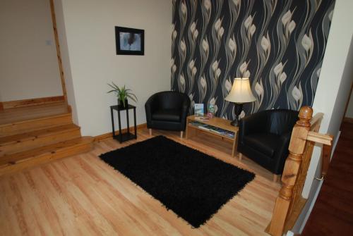a living room with two chairs and a rug at Aaranmore Lodge Guest House in Portrush