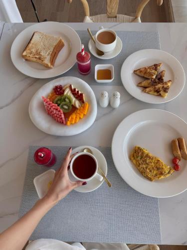 a table with plates of food and a person holding a cup of coffee at Khoj Resorts Allana in Karachi